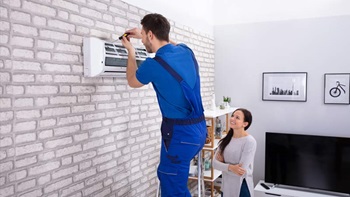 técnico a instalar unidade interior de aparelho de ar condicionado na sala de uma cliente